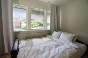 a bedroom with a white bed with two windows at Nyrenoverad lägenhet med perfekt läge nära Elmia in Huskvarna