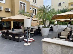 a patio with tables and umbrellas and chairs at The Sojourner By Genesis in Ikeja