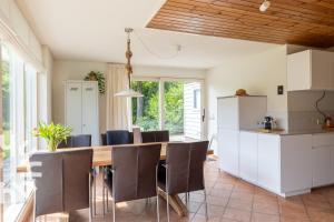 a kitchen and dining room with a wooden table and chairs at Vrijstaande vakantiewoning dichtbij het Veerse Meer in Wolphaartsdijk +12 photos