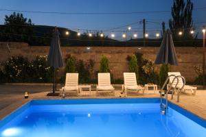a swimming pool with chairs and umbrellas at night at TN Guest House in Nor Geghi