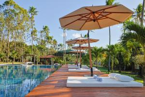 a row of lounge chairs with umbrellas next to a swimming pool at Eco Luar Boutique Hotel in Igarassu