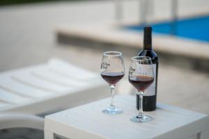 two glasses of red wine next to a bottle of wine at TN Guest House in Nor Geghi