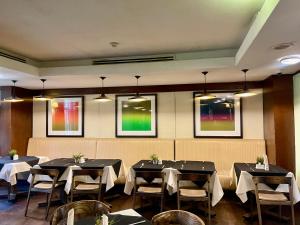 a dining room with tables and chairs and paintings at The Sojourner By Genesis in Ikeja