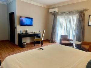 a hotel room with a bed and a desk and a television at The Sojourner By Genesis in Ikeja
