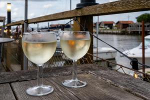 two glasses of white wine sitting on a wooden table at Superbe T2 lumineux plein centre in Audenge