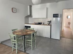 a kitchen with a table and chairs and a refrigerator at Le Bastide l 2 chambres l Rez-de-chaussée l Terrasse l Clim in Sémalens