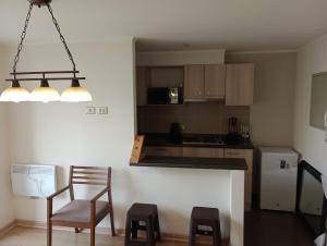 a kitchen with a counter and two chairs and a table at Departamento nuevo 3 dormitorios, Temuco in Temuco
