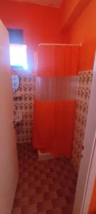 a bathroom with a shower with an orange wall at Love Greece Dream Pavlaras in Tolo