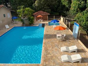 a swimming pool with chairs and umbrellas next to a house at Ananda pousada chalé in São Pedro
