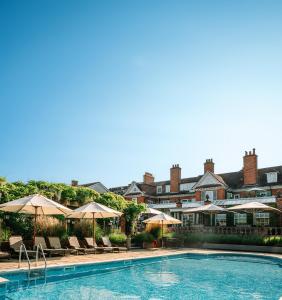 a pool with umbrellas and chairs and a hotel at Chewton Glen Hotel - an Iconic Luxury Hotel in New Milton