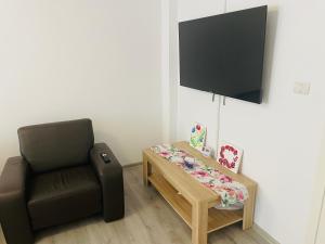 a room with a chair and a table and a flat screen tv at Cazare Balo in Zărneşti