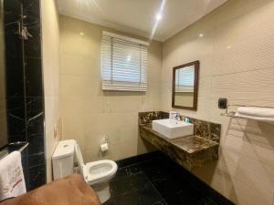 a bathroom with a toilet and a sink and a mirror at The Sojourner By Genesis in Ikeja