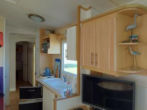 a kitchen with a sink and a tv in a caravan at Arizona Caravan in Camber