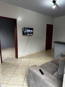 a living room with a couch and a tv on a wall at Casa completa privativa in Foz do Iguaçu