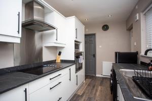 a kitchen with white cabinets and a black counter top at Modern Interior Spacious Four Bedroom Apartment in Westoe +15 photos