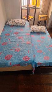 a bed with a blue comforter with roses on it at CENTRO DO PELOURINHO in Salvador