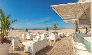 a boardwalk with white chairs and tables on the beach at San Borja Boutique 1 in Gandía