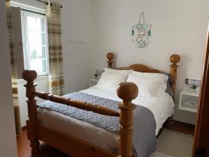 a bedroom with a wooden bed with white pillows at Casa Do Gerardo in Nazaré