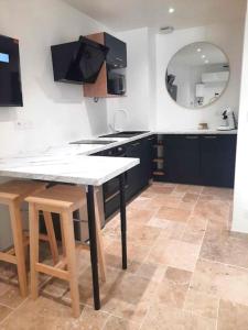 eine Küche mit einem Tisch, einem Waschbecken und einem Spiegel in der Unterkunft Studio 2 - Appart' hôtel avec terrasse - TU ELLETA in Tulette + 22 Fotos