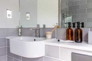 a bathroom with a sink with bottles on a counter at Sandpipers, Port Isaac Bay Holidays in Port Isaac +21 photos
