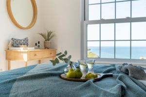 a tray of pears on a bed with a view of the ocean at Sandpipers, Port Isaac Bay Holidays in Port Isaac