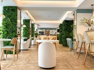 a restaurant with white tables and chairs and green walls at Hôtel Victoria in Cannes