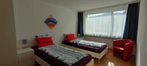 a bedroom with two beds and a red chair at Davos - Cozy Escape - Mountain Rentals in Davos +11 photos