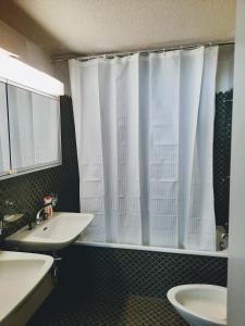 a bathroom with a sink and a white shower curtain at Davos - Cozy Escape - Mountain Rentals in Davos