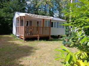 ein kleines Haus mit einer Veranda und einer Terrasse in der Unterkunft Bungalow charmant avec piscine partagée à Saint-Chéron in Saint-Chéron