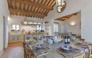 a large kitchen with a table with plates and wine glasses at Villa Lotus Magliano in Magliano in Toscana