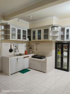a kitchen with white cabinets and white tile floors at Villa Kota Bunga AA2-11 in Cikundul