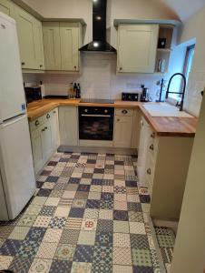 a kitchen with white cabinets and a tile floor at Hebron Rural converted chapel in Nantglyn