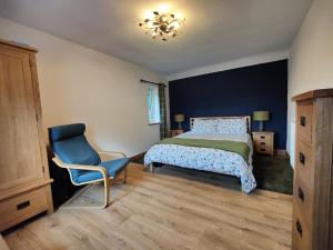 a bedroom with a bed and a blue chair at Hebron Rural converted chapel in Nantglyn