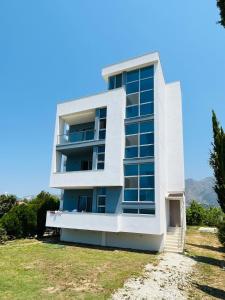 een wit gebouw met blauwe ramen op een heuvel bij River Residence in Orikum