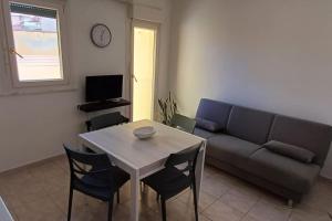 a living room with a couch and a table and chairs at Marida - Dimora moderna in centro storico in SantʼAntìoco