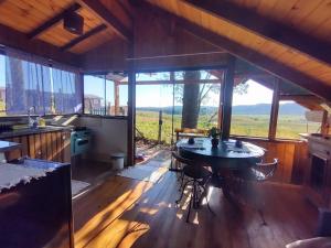 a kitchen with a table in a room with windows at Na'raucária in Cambará