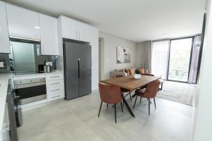 a kitchen with a wooden table and chairs in a kitchen at Summerstrand Escape Bella Mare in Gqeberha