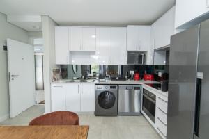 a kitchen with white cabinets and a dishwasher at Summerstrand Escape Bella Mare in Gqeberha