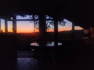 a silhouette of a table in a room with a sunset at Na'raucária in Cambará