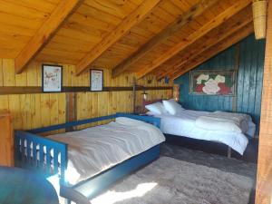 two beds in a room with wooden walls at Na'raucária in Cambará
