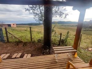 a wooden bench sitting on a porch next to a tree at Na'raucária in Cambará