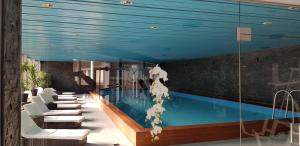 a swimming pool with white chairs and a blue ceiling at Davos - Cozy Escape - Mountain Rentals in Davos
