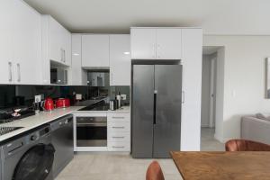 a kitchen with white cabinets and a stainless steel refrigerator at Summerstrand Escape Bella Mare in Gqeberha