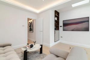 a white living room with a couch and a table at Newly refurbished cosy 2 bed in Wembley in London