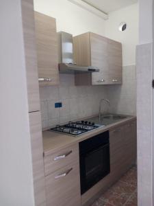 Una cocina con gabinetes de madera y un horno de estufa. en FRONTE MARE apartment, en Barcellona-Pozzo di Gotto