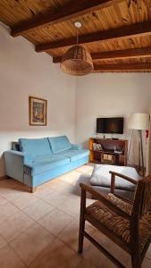 Una sala de estar con un sofá azul y un televisor. en La Bignonia Posada, en Chacras de Coria