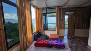 a bedroom with a bed in a room with windows at Munsong Norling Homestay - A unit of Dhitang- Offbeat Kalimpong in Pedong