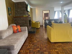 a living room with couches and a stone fireplace at My Lily Cottage Naivasha in Naivasha