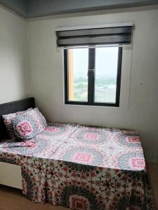 a bed in a room with a window and a bedspread at Centro Tower - 2 Bedroom Fully Furnished in Manila