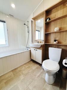 a bathroom with a toilet and a tub and a sink at 2 Lakeside, Luxury lodge with private garden & parking in Patrington